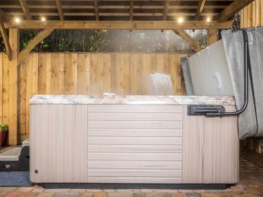An outdoor hot tub with a wooden shelter and a folded cover at New Peny in Llandrindod Wells