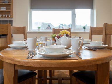 A dining table set with white dishes cups a teapot and a fruit bowl at New Peny in Llandrindod Wells