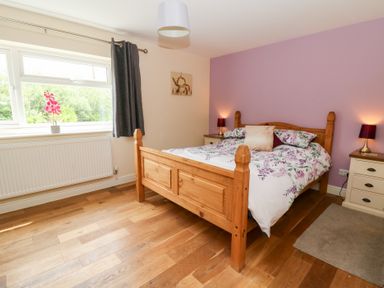 A bedroom with a wooden bed and window at New Peny in Llandrindod Wells