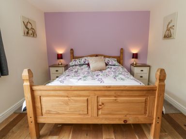A bedroom featuring a wooden bed with floral bedding at New Peny in Llandrindod Wells
