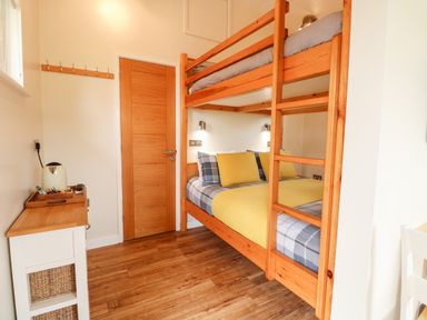 A bedroom with wooden bunk beds a wooden door and a small cabinet with a kettle at Bramble in Banham
