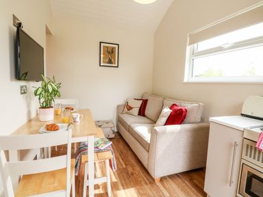 A dining table with croissants and drinks next to a beige sofa with cushions in a small living room at Bramble in Banham