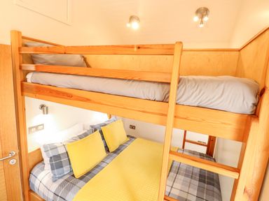 A bedroom with wooden bunk beds and plaid bedding with yellow pillows at Bramble in Banham
