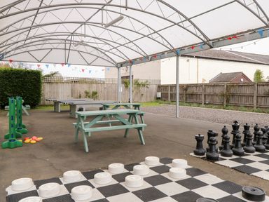 A covered outdoor area with picnic tables table tennis and large chess and checkers boards at Bramble in Banham