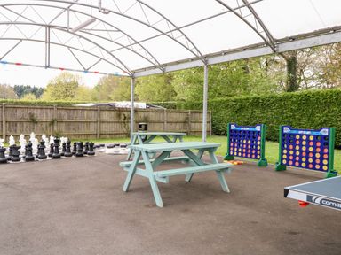 An outdoor covered area with picnic tables giant chess set giant connect four games and a ping pong table at Bramble in Banham