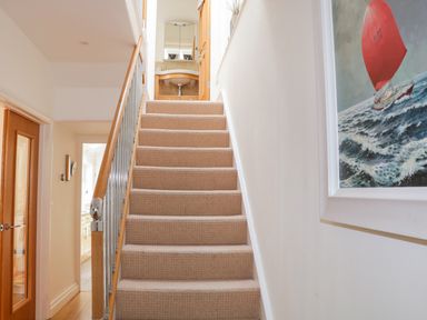 A carpeted staircase with a wooden handrail leading to a small bathroom at 1 Orchard Cottages in Salcombe