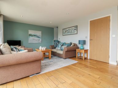 A living room with two brown sofas a wooden coffee table and side table with a lamp and two paintings at Lodge Sixty Six in St Columb Major