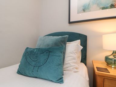 A bed with blue pillows and a bedside table with a lamp at Lodge Sixty Six in St Columb Major
