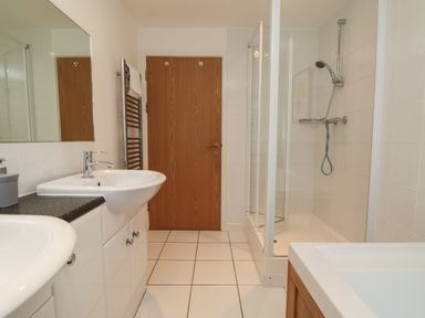 A bathroom with a sink, shower, bathtub, towel rack, and wooden door at Lodge Sixty Six in St Columb Major