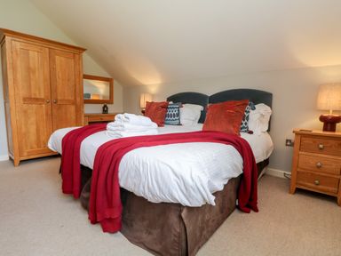 A bedroom with two beds pushed together with white linens and red throws at Lodge Sixty Six in St Columb Major