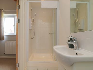 A bathroom with a shower enclosure and a sink with a faucet at Lodge Sixty Six in St Columb Major