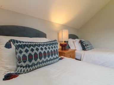 A bedroom with two single beds with blue patterned pillows and a nightstand with a lit lamp between them at Lodge Sixty Six in St Columb Major