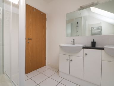 A bathroom with two sinks a large mirror a wooden door and a shower at Lodge Sixty Six in St Columb Major