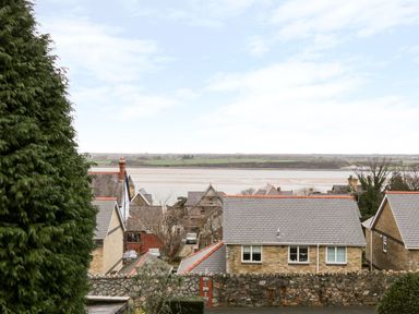 A view of houses with pitched roofs near a river and fields in the background at Preswylfa Apartment in Caernarfon