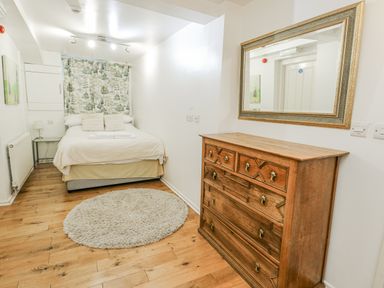 A bedroom with a bed, dresser, and mirror at Preswylfa Apartment in Caernarfon