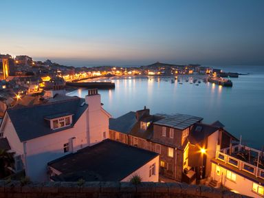 A coastal town with houses and a harbor with boats at dusk at Miner's Rest in Troon near Camborne