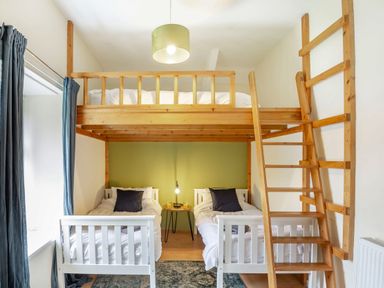 A bedroom with two single beds under a wooden loft bed with ladder and a small table between the single beds at Stiniog Lodge in Blaenau Ffestiniog