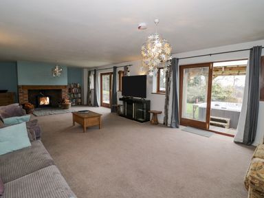 A living room with a fireplace a TV a coffee table and sliding glass doors leading outside at Shatterford Lakes in Shatterford