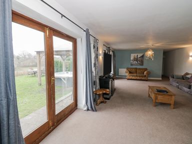 A living room with sofas a coffee table a television and glass doors leading to a garden at Shatterford Lakes in Shatterford