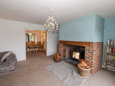 A living room with a fireplace wood baskets and a bookshelf near a dining area at Shatterford Lakes in Shatterford