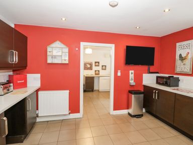 A kitchen with red walls dark cabinets a microwave a toaster a bread box and a wall-mounted television at Shatterford Lakes in Shatterford