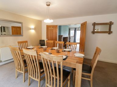 A dining room with a wooden table and eight chairs plates and glasses on the table at Shatterford Lakes in Shatterford