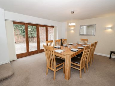 A dining room with a wooden table and eight chairs set with plates and glasses at Shatterford Lakes in Shatterford