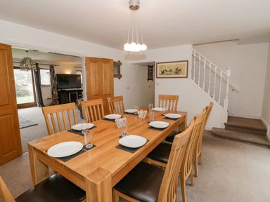 A dining room with a wooden table set with plates and glasses adjacent to a staircase at Shatterford Lakes in Shatterford