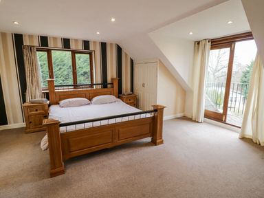 A bedroom with a wooden bed two wooden nightstands carpeted floor and double glass doors at Shatterford Lakes in Shatterford