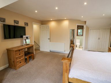 A bedroom with a wooden bed desk and television mounted on the wall at Shatterford Lakes in Shatterford
