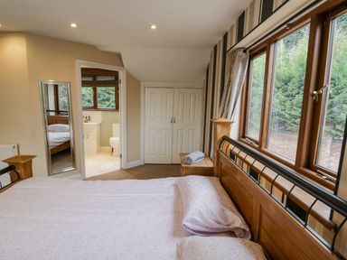 A bedroom with a bed pillow and blanket near a window a wooden cabinet and an open door leading to a bathroom at Shatterford Lakes in Shatterford