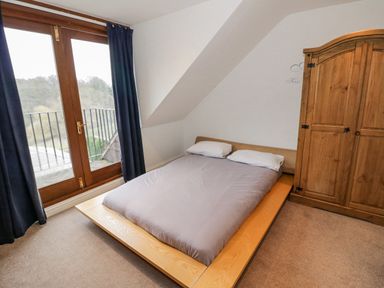 A bedroom with a double bed next to wooden closet and glass door with curtains at Shatterford Lakes in Shatterford