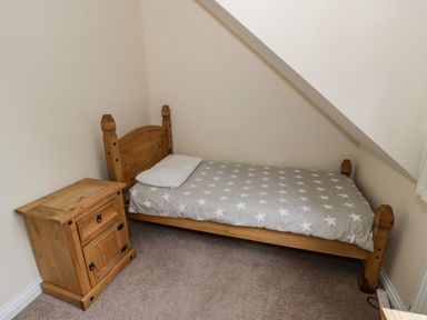 A small bedroom with a single wooden bed with star patterned bedding and a wooden bedside cabinet at Shatterford Lakes in Shatterford
