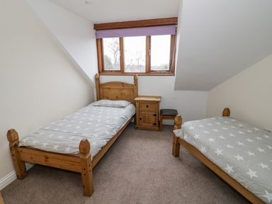 A bedroom with two single wooden beds a wooden bedside table and a window with a purple blind at Shatterford Lakes in Shatterford