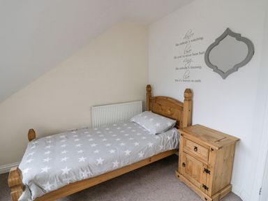 A bedroom with a single wooden bed with star-patterned bedding and a wooden bedside table at Shatterford Lakes in Shatterford