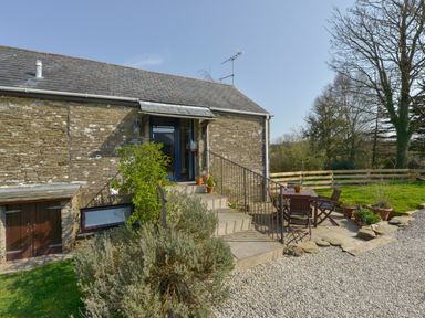 A stone cottage entrance with stairs and outdoor table and chairs in a garden at Erin Cottage in Pelynt near Looe