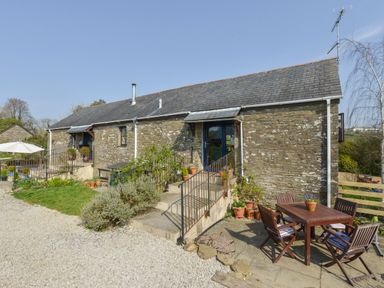 A stone cottage with outdoor seating and potted plants at Erin Cottage in Pelynt near Looe