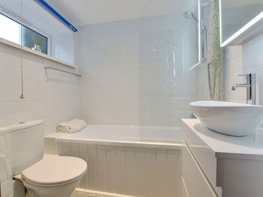 A bathroom with a toilet bathtub with a towel a shower and a sink at Erin Cottage in Pelynt near Looe