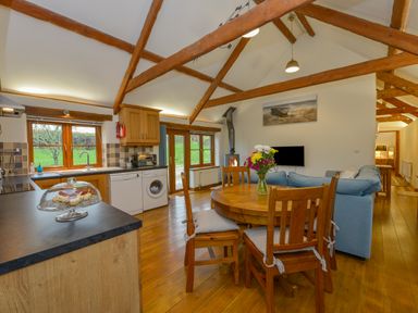 A kitchen and dining area with wooden furniture and beams at Hook Cottage in Pelynt near Looe