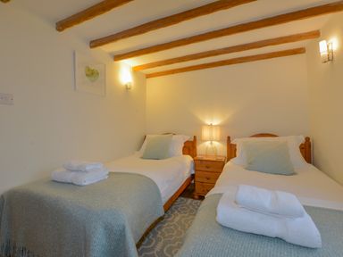A bedroom with two single beds with blue blankets and pillows at Hook Cottage in Pelynt near Looe