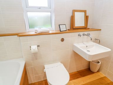 A bathroom with a toilet sink bathtub mirror and a window at 1 Lake View in Lanreath