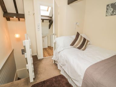 A small bedroom with a single bed next to a door leading to a bathroom at Wren Cottage in Morpeth