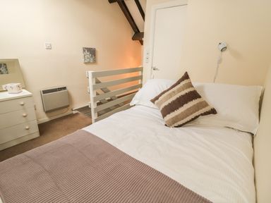 A bedroom with a bed white dresser heater and a small painting at Wren Cottage in Morpeth