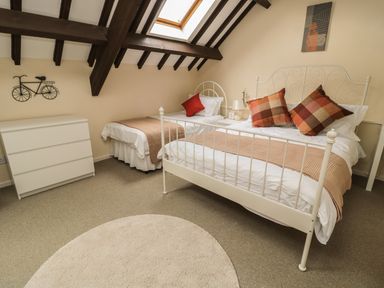 A bedroom with two beds a chest of drawers and a circular rug at Heron Cottage in Morpeth