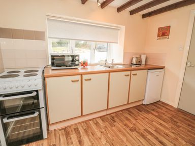 A kitchen with an electric stove microwave sink and refrigerator at Heron Cottage in Morpeth