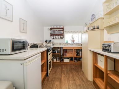 A kitchen with wooden shelves microwave toaster and a window at Owl Barn in Tavistock