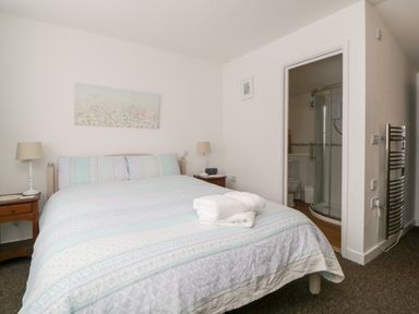 A bedroom with a double bed bedside tables and a bathroom at Owl Barn in Tavistock