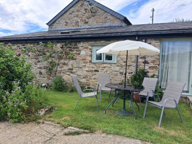 A garden with a table and chairs at Owl Barn in Tavistock
