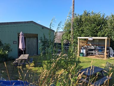 A garden with a shed, outdoor table, and cooking area at Owl Barn in Tavistock