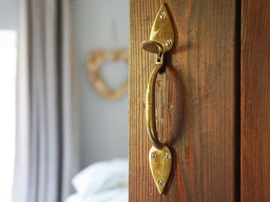 A close up of a brass door handle on a wooden door with a blurred bedroom background at Cae Lleci Llanfachreth near Dolgellau